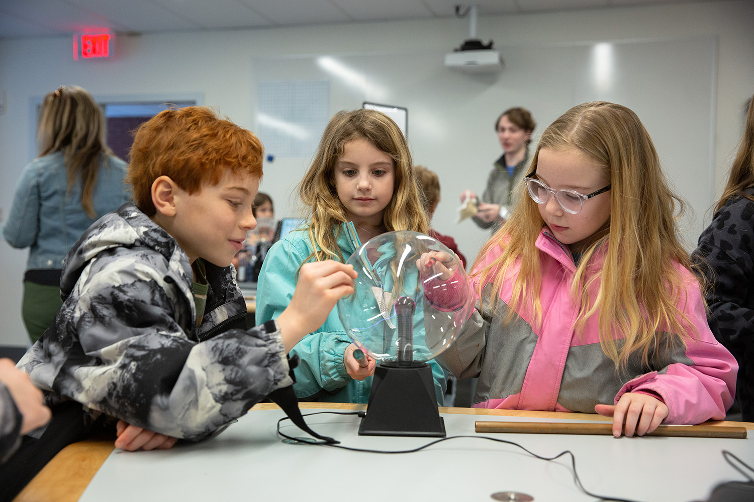 Students touch a plasma ball during a physics outreach event.