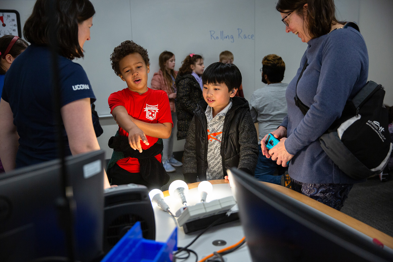 A student points to a light during a physics outreach event.