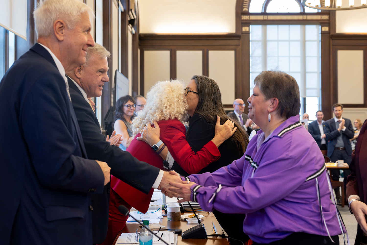 UConn President Radenka Maric hugs Beth Regan, chairwoman and justice of the Mohegan Tribal Nation, shakes hands with members of UConn's Board of Trustees during the boards' meeting in the North Reading Room of Wilbur Cross