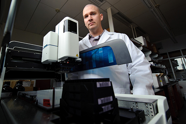 Kyle Hadden, assistant professor of Pharmaceutical Science, in the lab with a liquid handling machine on Nov. 14, 2011. (Peter Morenus/UConn Photo)