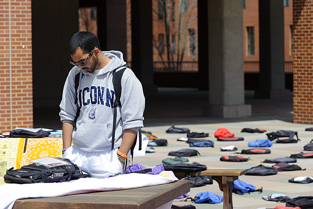 David Vidaurre '14 (CLAS) looks at a note attached to one of 1,100 backpacks, representing the number of college students who die by suicide each year cover the Homer Babbidge Library Plaza on April 12, 2012. (Peter Morenus/UConn Photo)