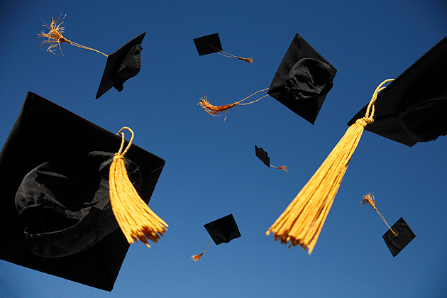 Group of mortar board caps being thrown in the air.