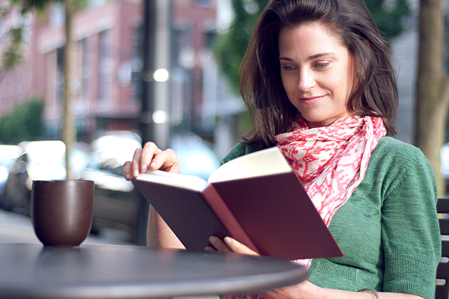 Woman reading book with cup of coffee.