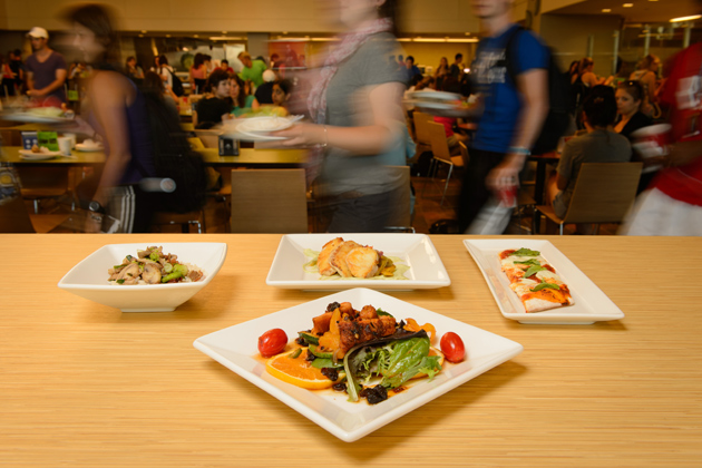 A plate of spice rubbed chicken over mixed greens with dried fruit and orange, front, with xiachao niugan jun, or stir-fried mushrooms with bacon, left, cod escabeche over tostones with an avocado cilantro crema, and margherita stone oven pizza at McMahon Dining on Aug. 31, 2012. (Peter Morenus/UConn Photo)