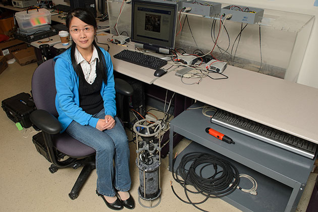 Zhaohui Wang, a Ph.D. candidate in engineering, sits in a lab next to the OFDM underwater modem on April 30, 2013. (Ariel Dowski/UConn Photo)