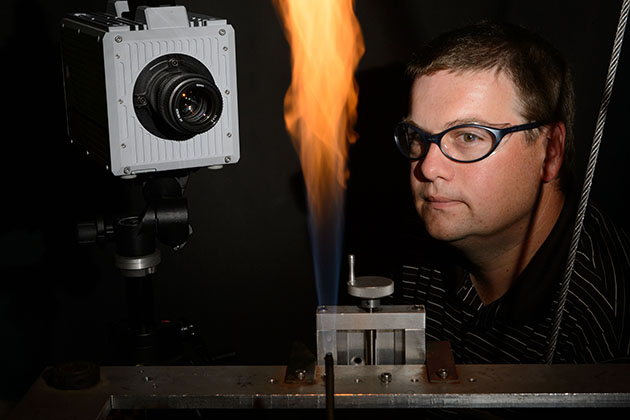 Michael Renfro, associate professor of mechanical engineering, observes a flame experiment on June 26, 2013. (Peter Morenus/UConn Photo)