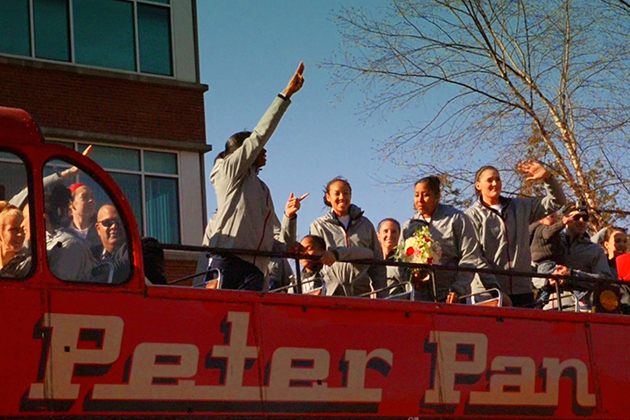 The women's basketball team greets the fans from the bus during a victory lap of campus on April 9. (Angie Reyes/UConn Photo)