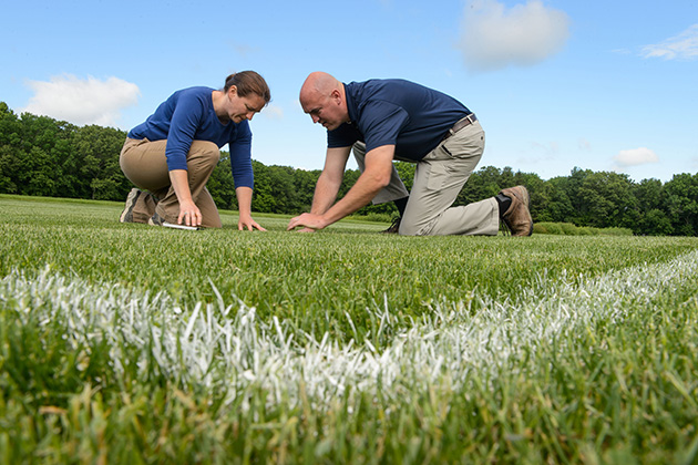 Jason Henderson, associate professor of plant science and landscape architecture, and Ph.D. student Julie Campbell, check a plot of turf for crabgrass and weeds on June 6, 2014. (Peter Morenus/UConn Photo)