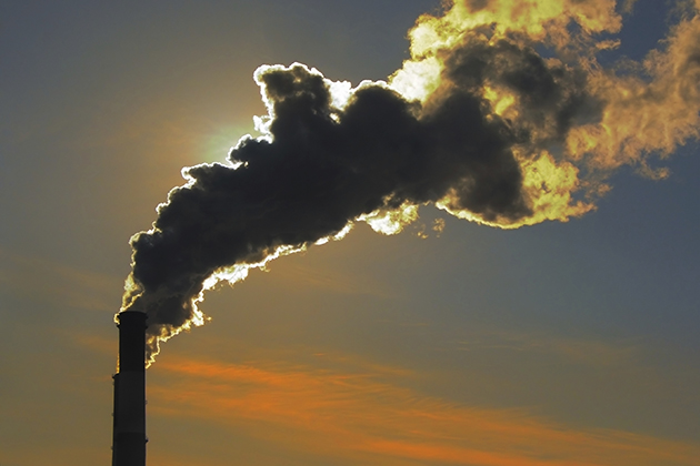 Silhouette of smoke stacks smoking up to the sky at sunset (iStock Photo)