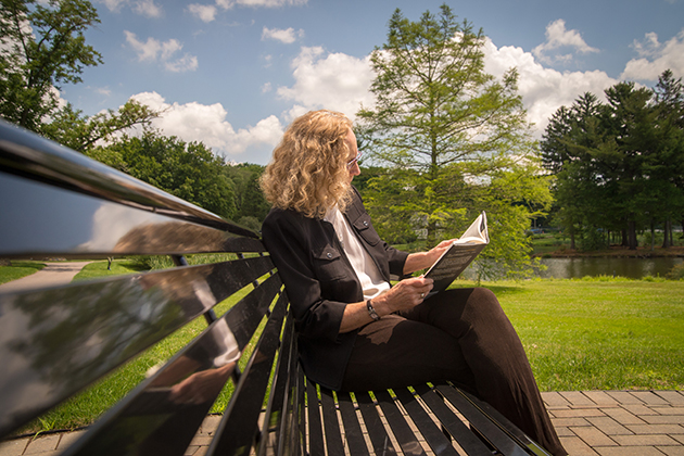 Sociology professor Nancy Naples, director of the Women's, Gender & Sexuality Studies Program, reads a book by Mirror Lake. (Sean Flynn/UConn Photo)