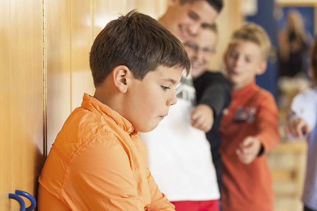 Schoolboys bullying a peer at school.