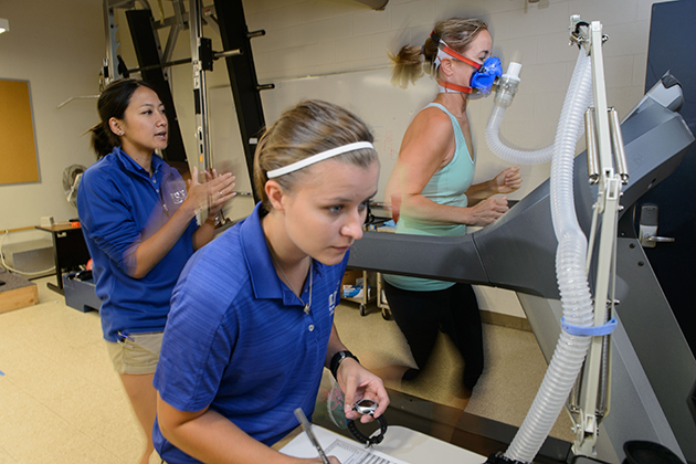 A woman soon to run in the Falmouth Road Race, right, is tested at the Korey Stringer Institute by Rachel Katch, center, and Yuri Hosokawa. (Peter Morenus/UConn Photo)