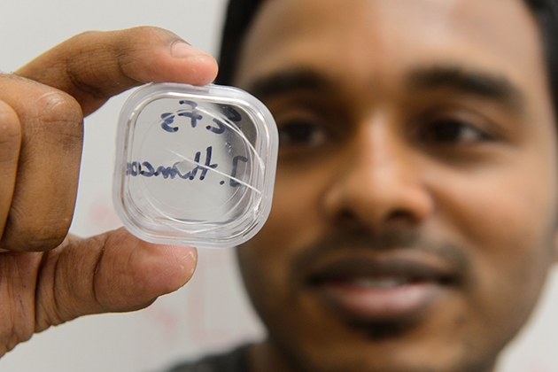 Sahan Handunkanda, a graduate student in physics and first author on the paper published by the American Physical Society, holds up a crystal of scandium trifluoride. (Peter Morenus/UConn Photo)