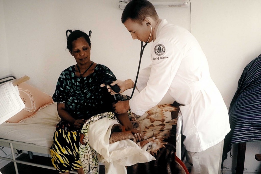 A medical student checks a patient's blood pressure during a visit to Uganda. (UConn Photo)