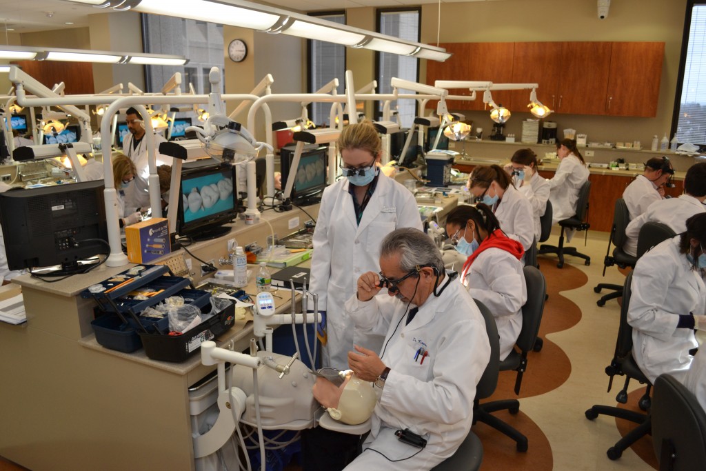 Dr. Reza Kazemi (seated in foreground), associate professor of operative dentistry and reconstructive sciences, demonstrates a dental technique to second-year dental student Jenna Marcinczyk (standing) in the Joseph E. Grasso Dental Simulation Lab. (Tina Encarnacion/UConn Health Photo)