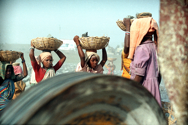 Girls carry heavy baskets of rock at a gravel quarry. (Robin Romano/UConn Archives & Special Collections)