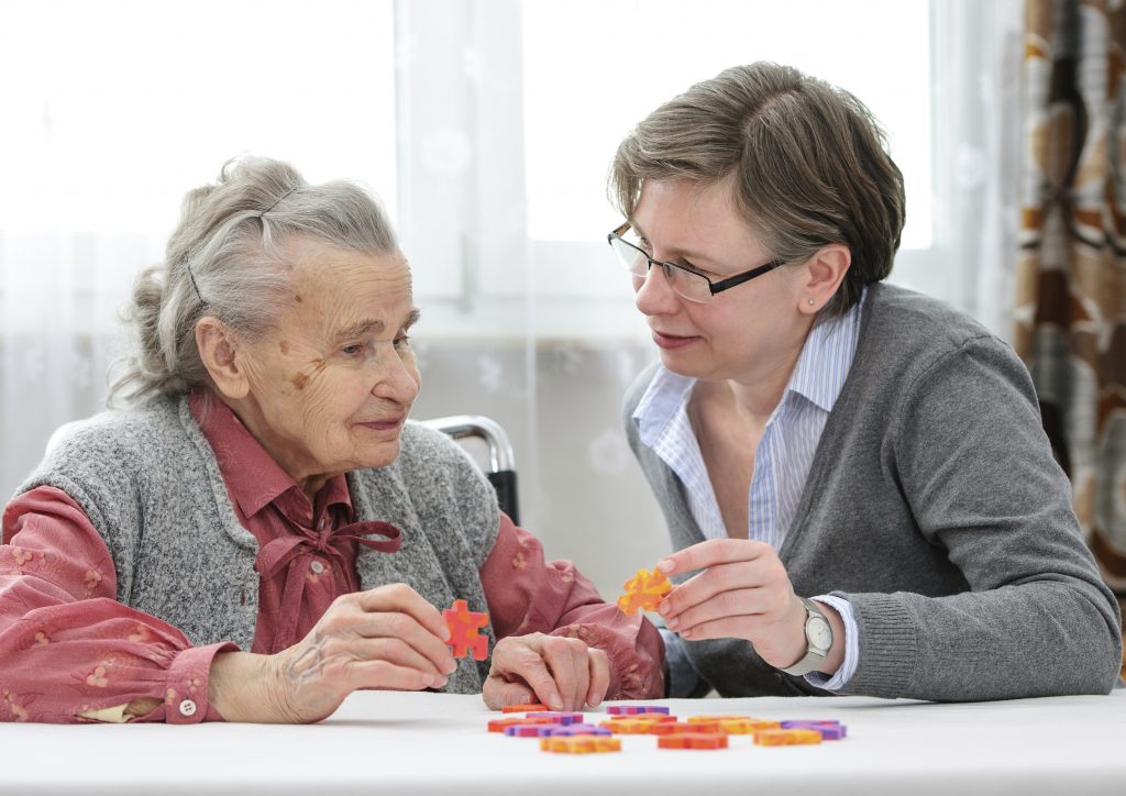 Elderly woman with caregiver figuring out a jigsaw puzzle at nursing home. (iStock Photo)