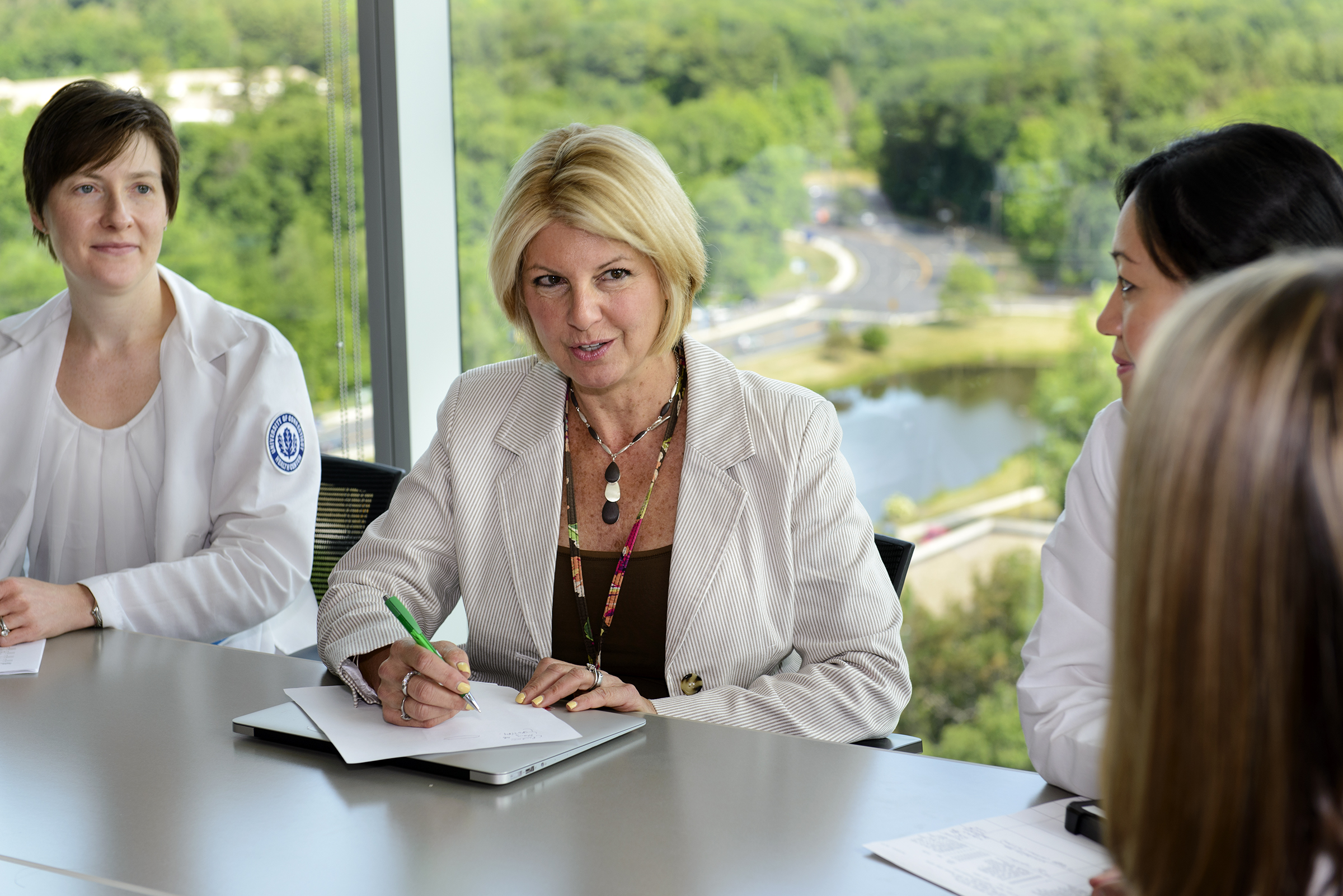 Dr. Dawn Murphy (center) meets with clinical staff in the University Tower, including nurse case managers Andrea Torres (left) and Catherine Zimmerman (right). In her role as a transitionist, Murphy discusses patients with hospital care teams, enabling continuity when she sees those same patients in a nursing home for their post-acute care. (Photo by Janine Gelineau)