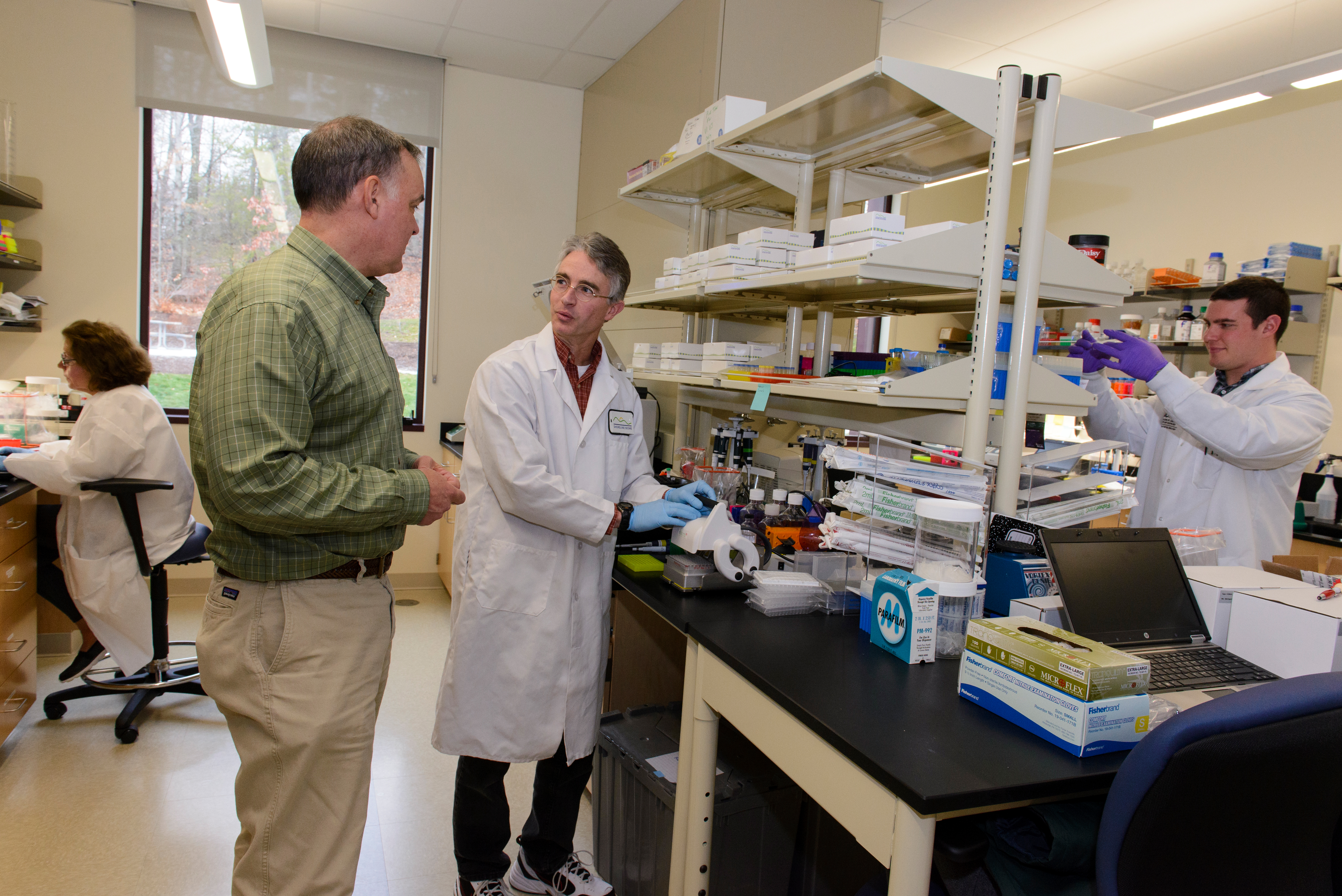 Chris Clark, Research Scientist; Tom Jarvie, CEO; Mark Driscoll, CSO; and Ryan Beach, Research Scientist. Jarvie and Driscoll are discussing the manufacturing process for the kits. (Janine Gelineau/UConn Health Photo)