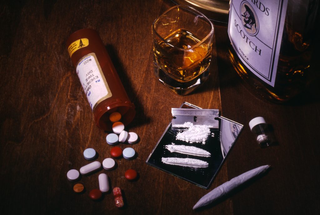 Tableau of drugs- pills, coke, marijuana, and alcohol.