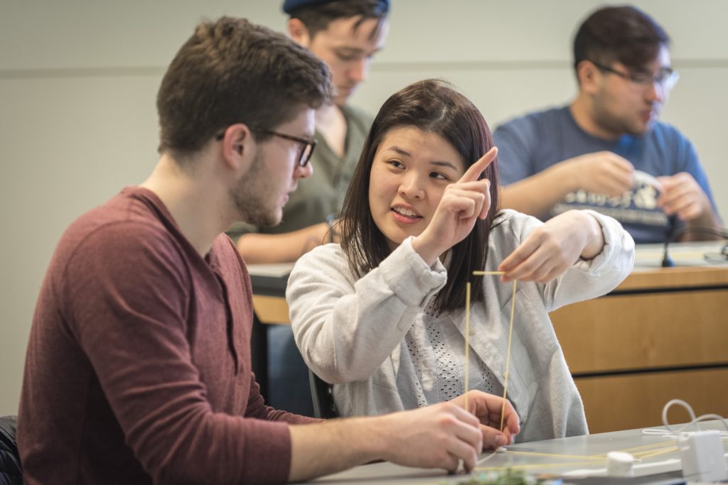 Undergraduates Richard Vincent III, left, and Cindy Lin discuss a hands-on exercise called 'Design Thinking: Marshmallow Challenge' during a class on incorporating game design into business planning. (Sean Flynn/UConn Photo)