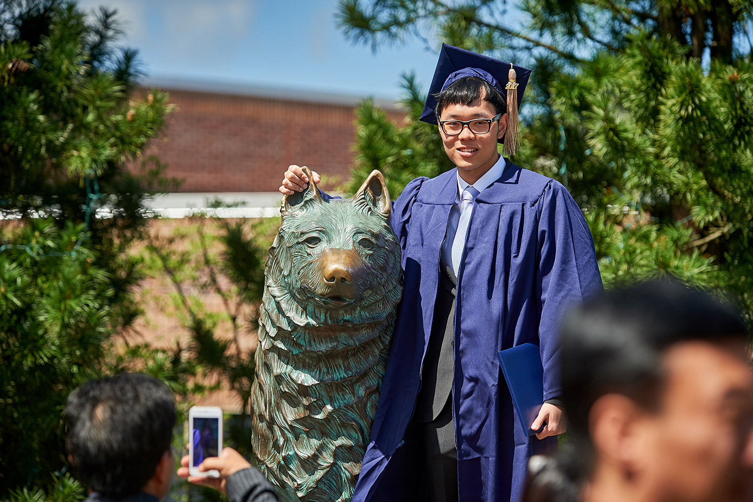 Bo Ni '17 (BUS) poses for a photo with the husky statue following the School of Business Commencement ceremony on May 7, 2017. (Peter Morenus/UConn Photo)