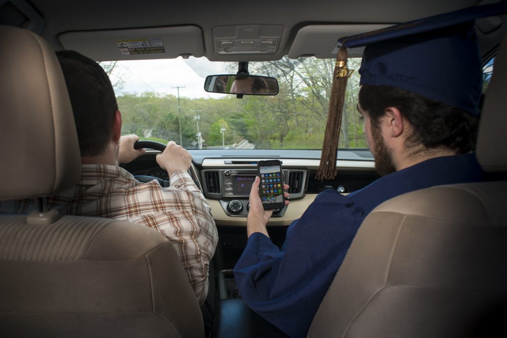 Graduating senior Brian Kelleher '17 (SFA), right, checks his phone for text messages. (Sean Flynn/UConn Photo)