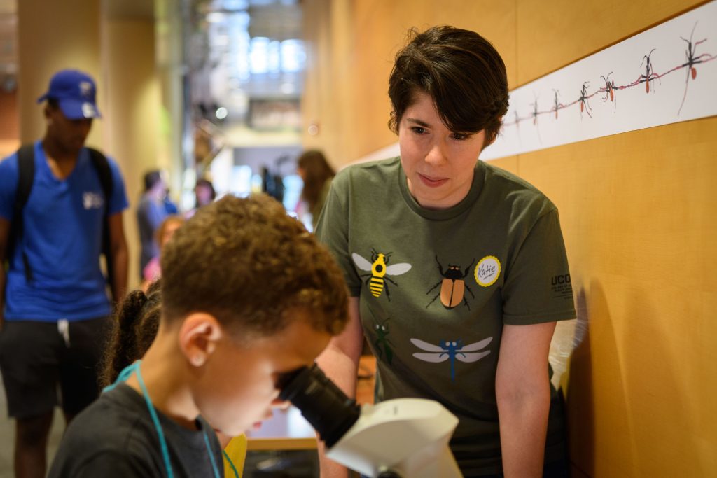 Katie Taylor, a Ph.D. student in ecology and evolutionary biology, tells visitors about samples under a microscope at the Biology/Physics Building during UConn Extension Bug Week AntU Day on July 27, 2017. (Peter Morenus/UConn Photo)