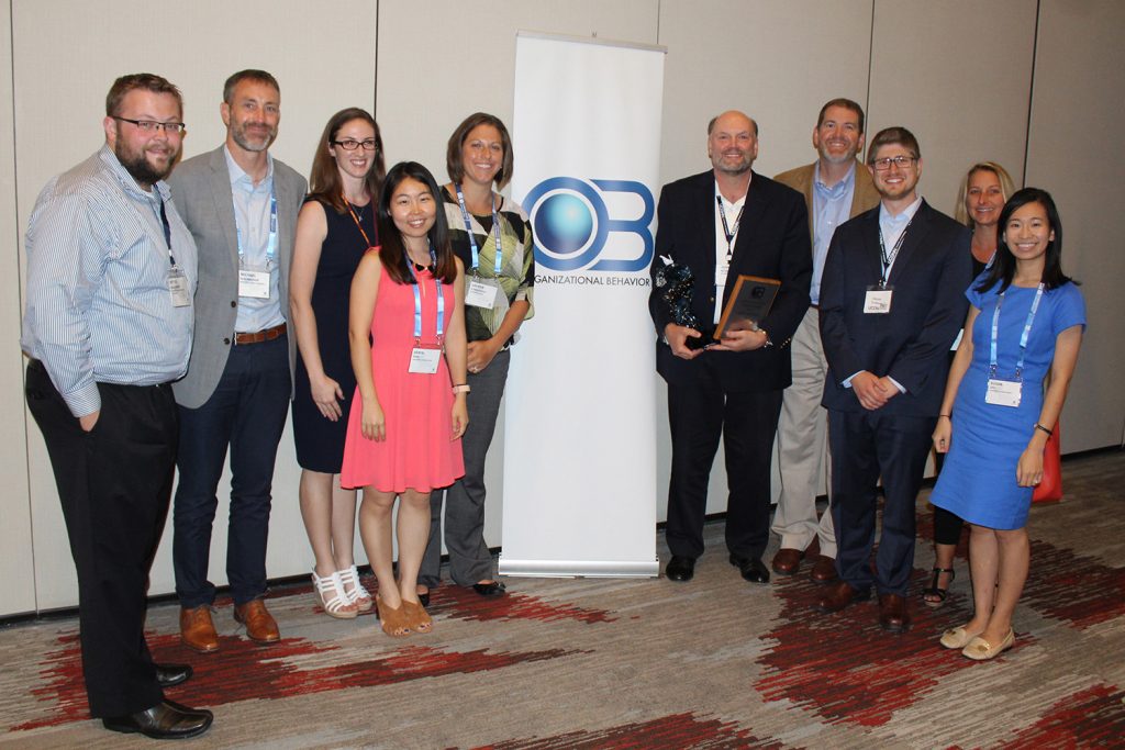 Mathieu receives his award from the Academy of Management, surrounded by past and present students. (John Mathieu/UConn School of Business)