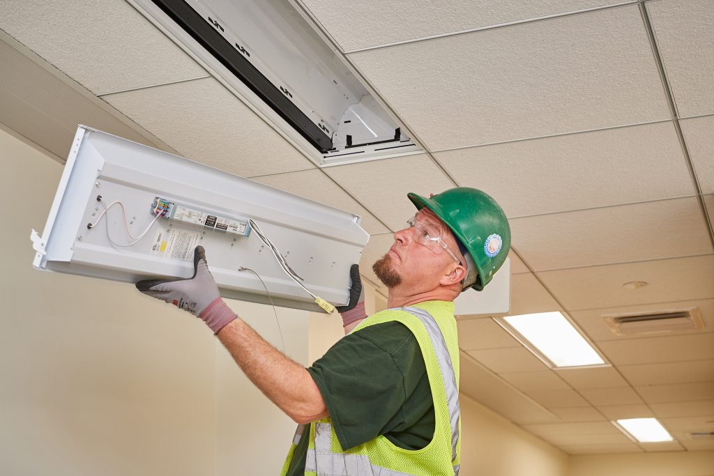 Kevin Michaud, a sub-contractor for conEdison Solutions, hangs a new LED light fixture in an office at the Biology/Physics Building. (Peter Morenus/UConn Photo)