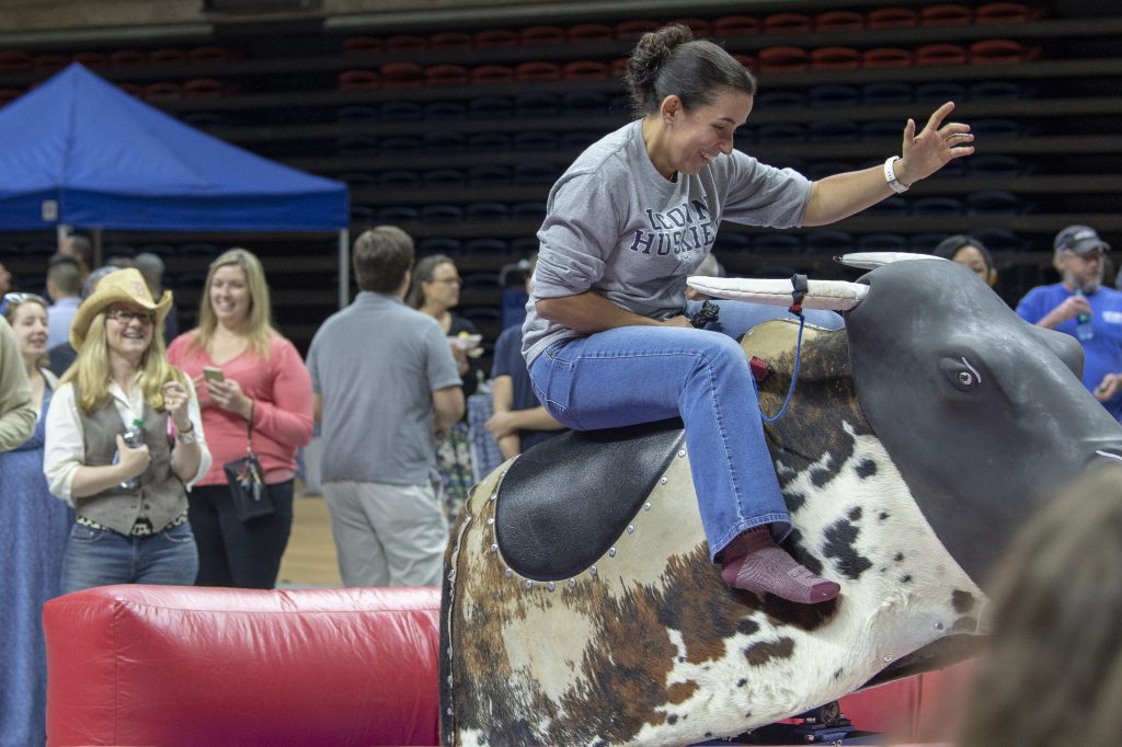 Angie Reyes of University Communications riding a mechanical bull at Employee Appreciation Day at Gampel Pavilion on May 10, 2018. (Sean Flynn/UConn Photo)