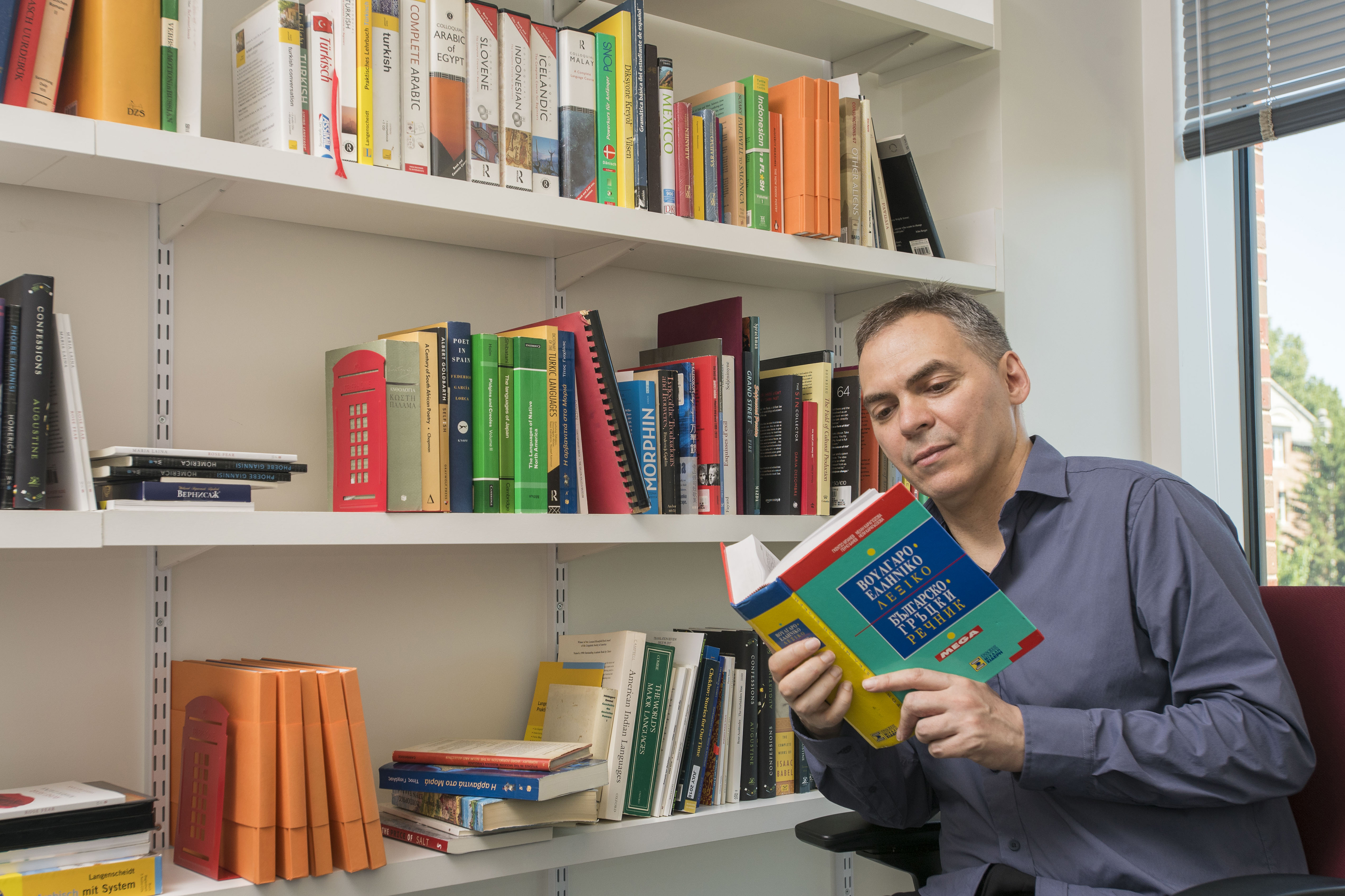 Translation expert Peter Constantine consults a Greek dictionary from the collection of the Department of Literatures, Cultures, & Languages. (Sean Flynn/UConn Photo)