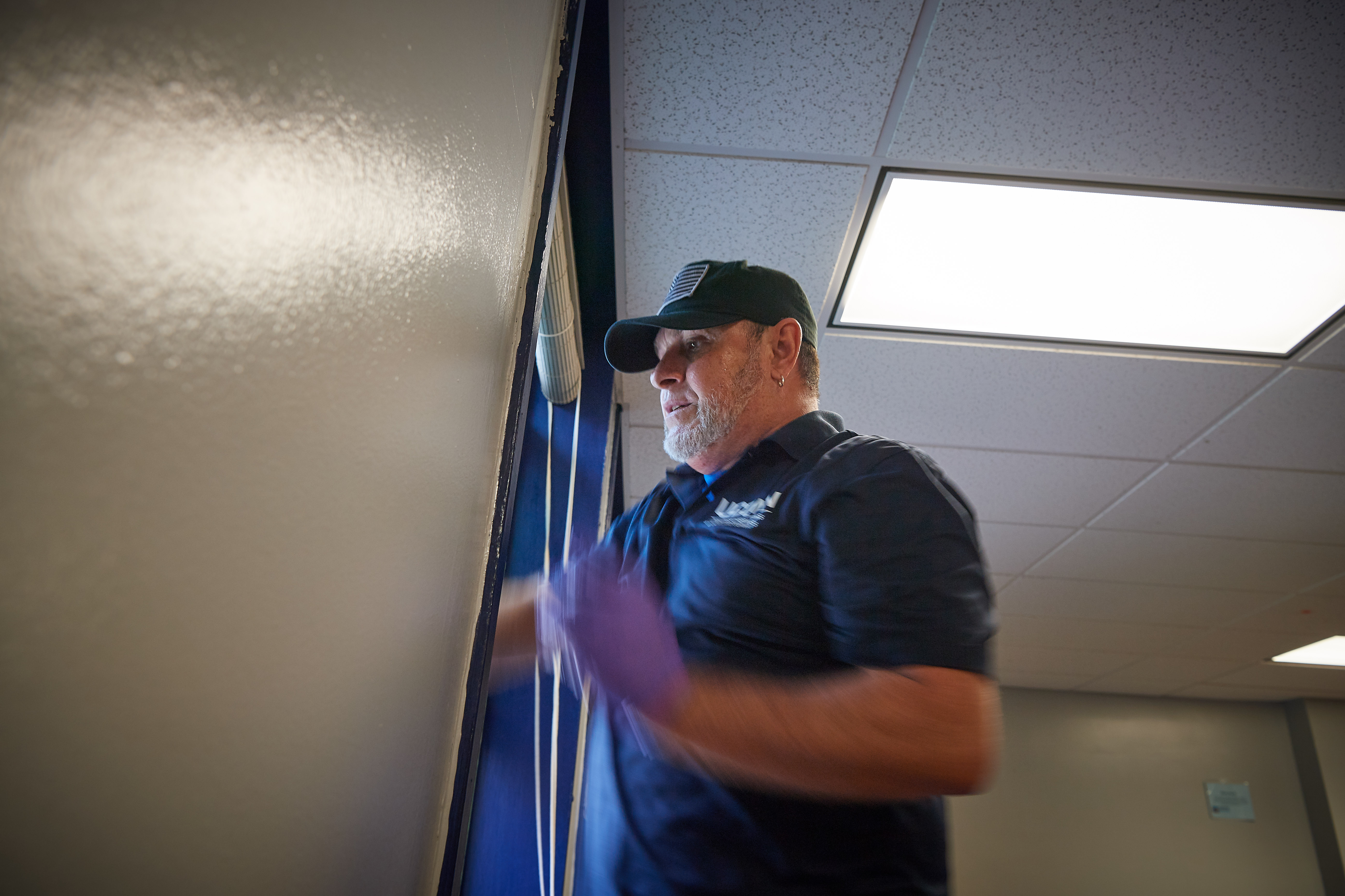 Lesme Valentin, a university custodian, cleans windows in a second floor lounge at Belden Hall onAug. 16, 2018. (Peter Morenus/UConn Photo)