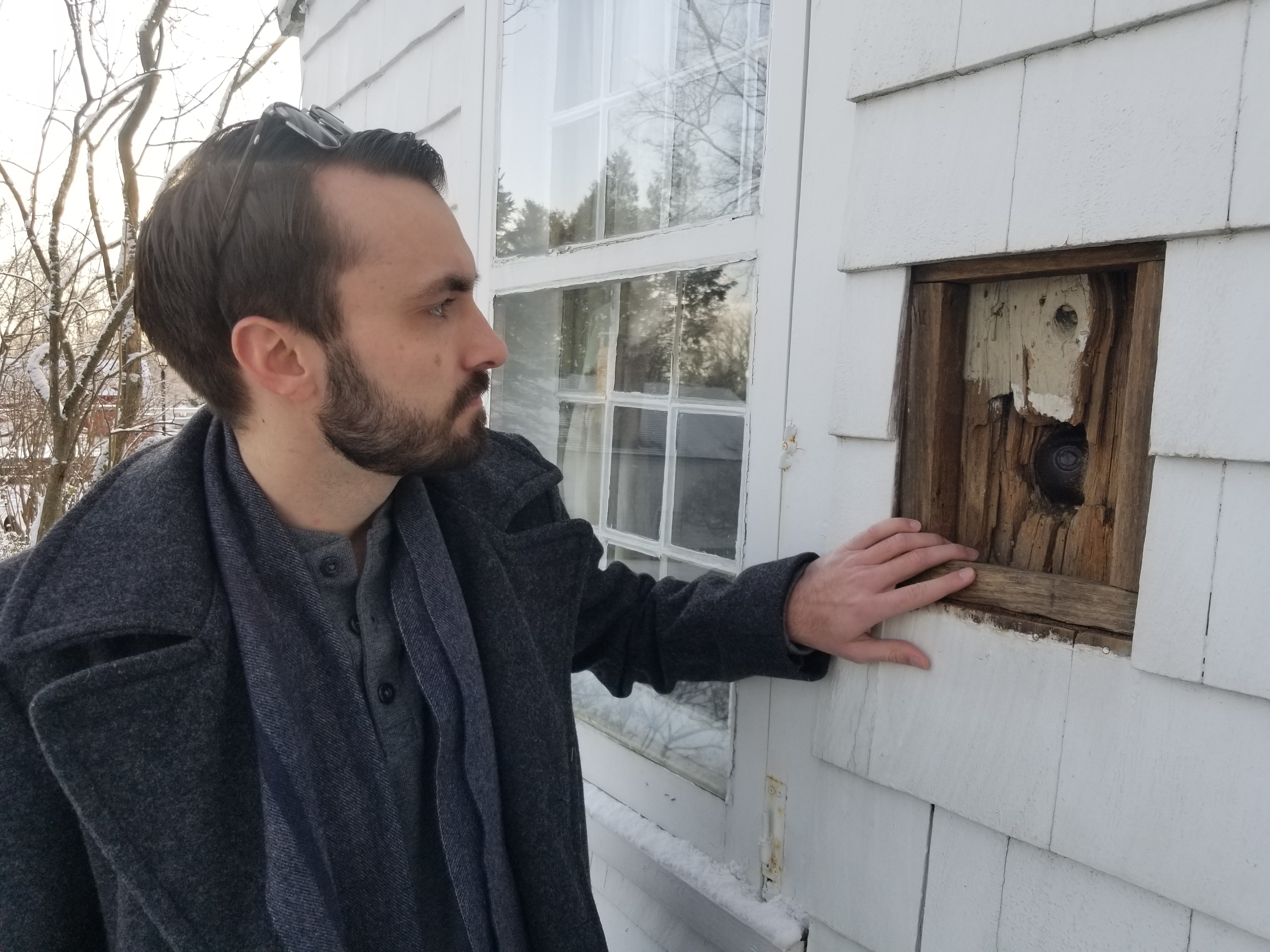 Man showing off a cannonball in a house wall.