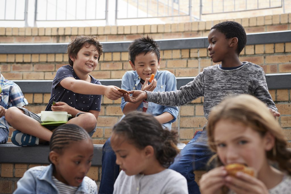 A group of young children having lunch together in a school cafeteria.