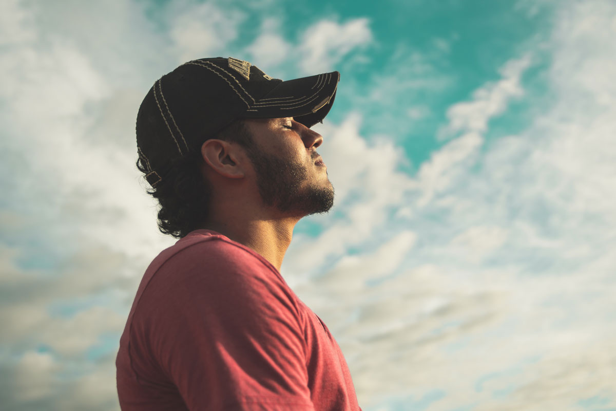 man wearing black cap under cloudy sky