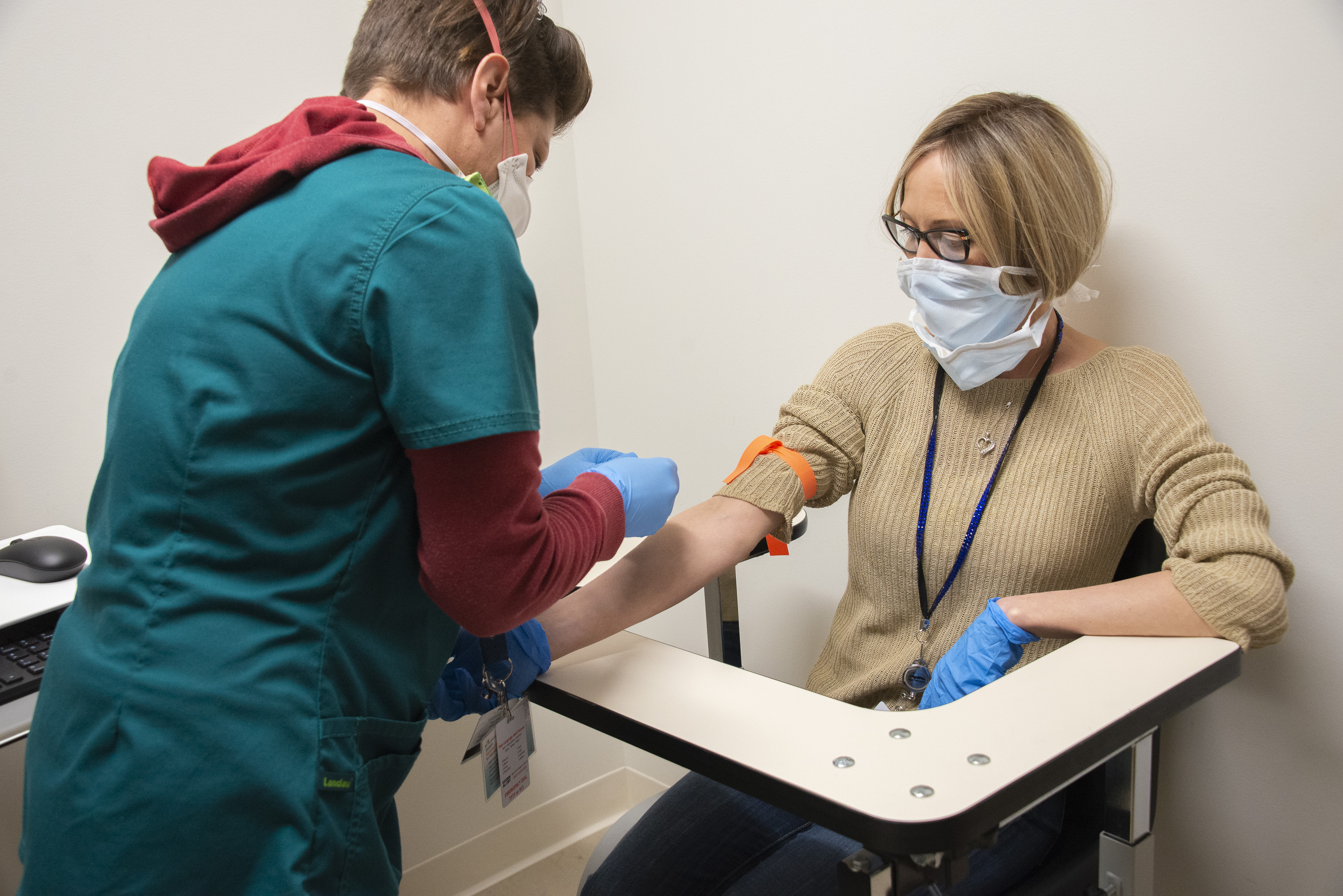 A woman with a surgical mask is prepared to donate blood.