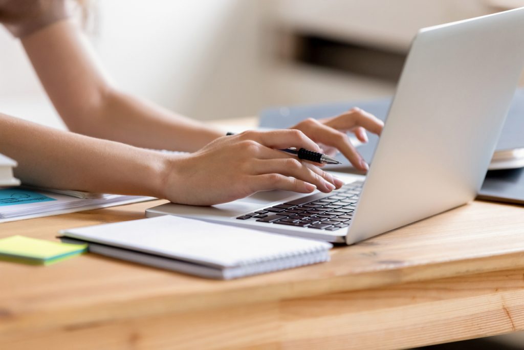 Female hands type onto laptop; learning during a pandemic.