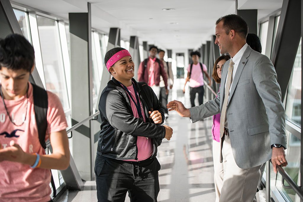 Neag School alum and school superintendent Nathan Quesnel greets a student at East Hartford High.