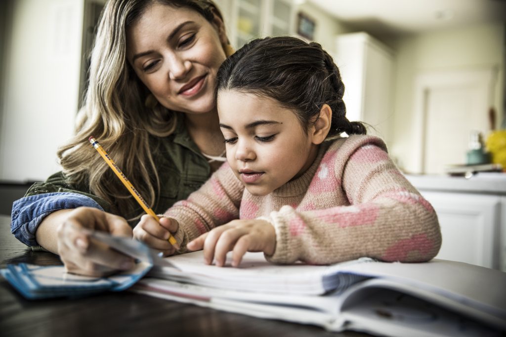 A mother and young daughter doing homework together.