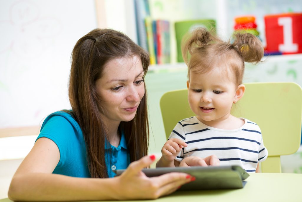 Parent holding tablet for child.