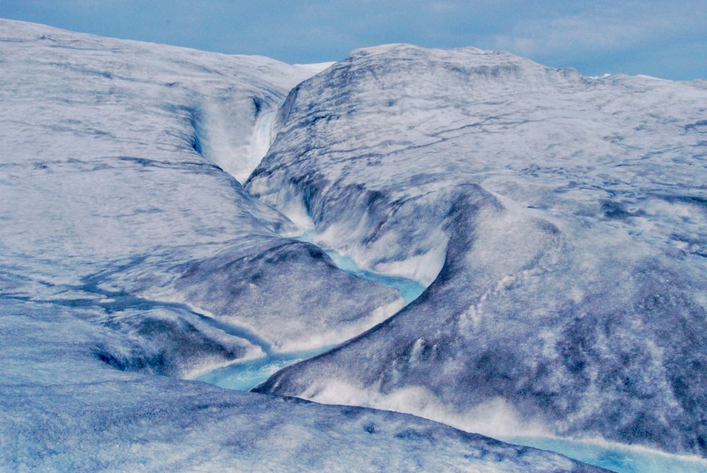 Meltwater pouring over ice at the edge of the Greenland Ice Sheet near 660 at midnight, Kangerlussuaq. Greenland.