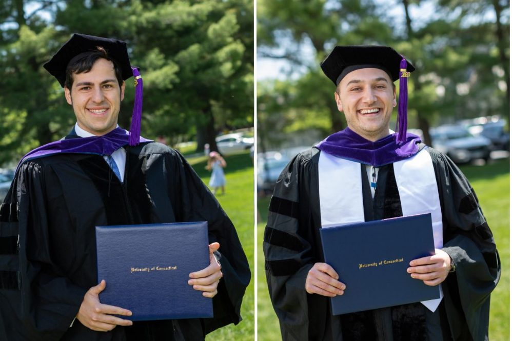 Eddie Batash and Periklis Fokaidis each pose in full commencement regalia displaying their diploma holders.