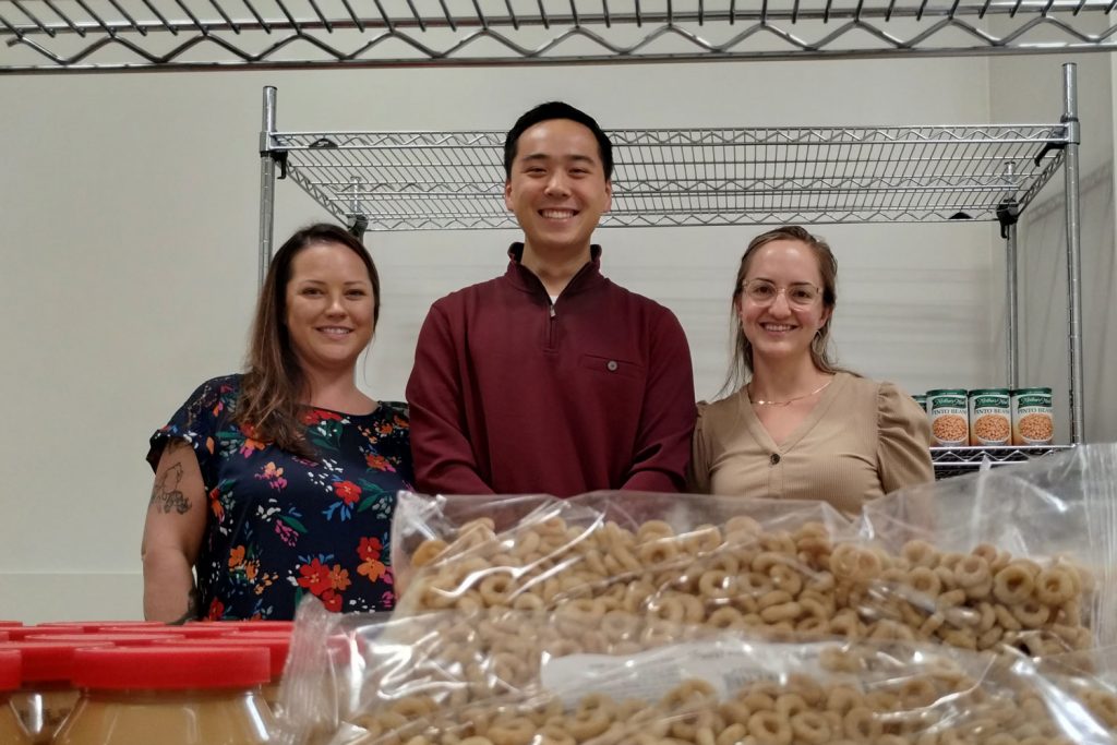 Group portrait behind food pantry shelf