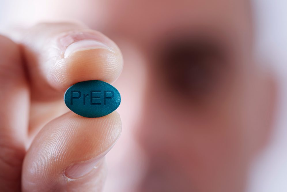 A young man holding a PrEP pill.