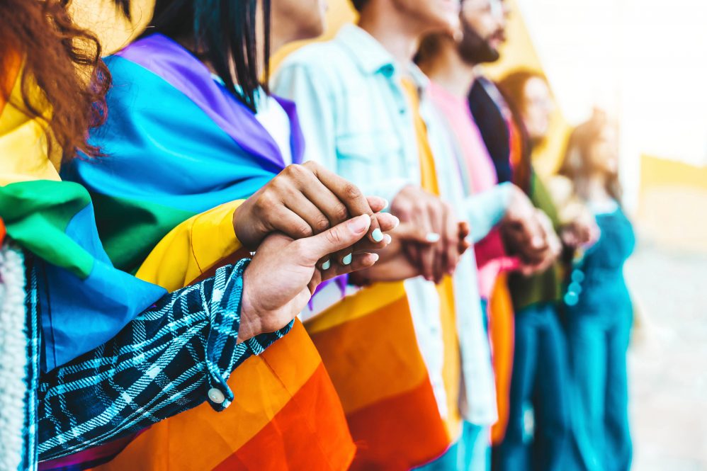 Group of lgbt people holding hands outside.