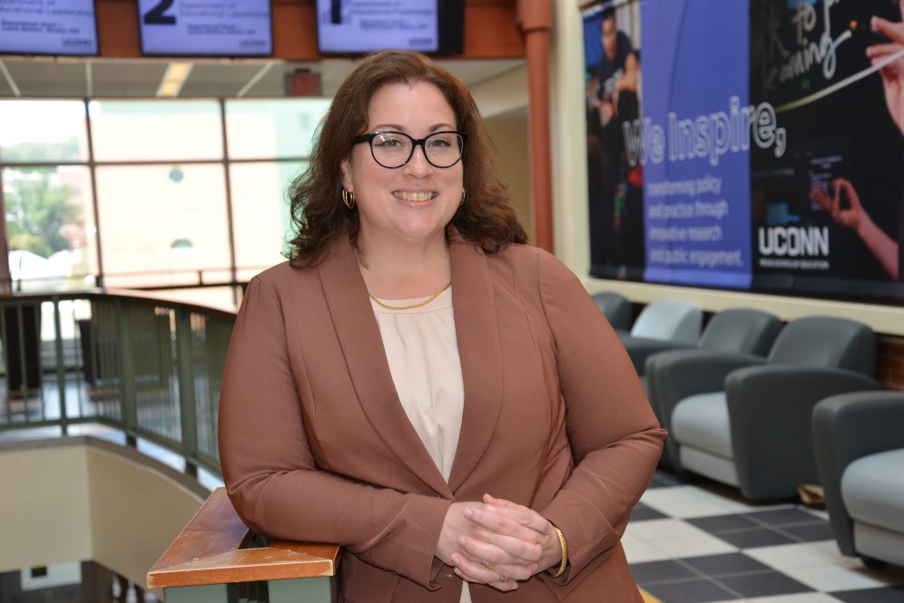 Rebecca Campbell-Montalvo smiles at the camera, wearing a blazer, blouse, and glasses.