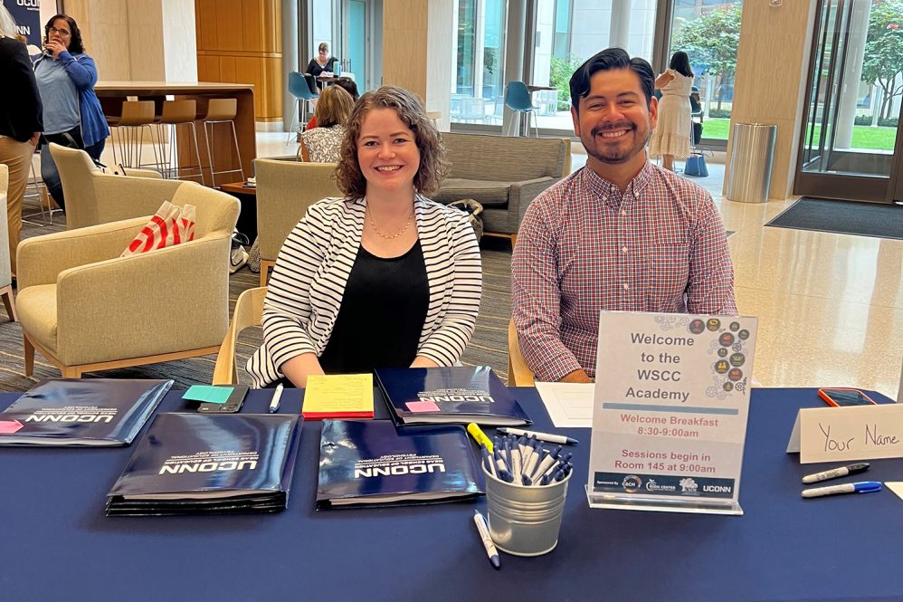 Two people sit at a welcome table.