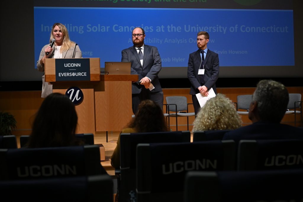 Graduate students Julie Sandberg, left, Kevin Howson and Jacob Hyler present their research on installing solar canopies on campus during "The Sustainable Clean Energy Summit:Decarbonizing Society and the Grid" at the Student Union Theater