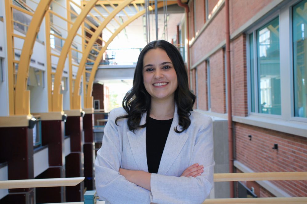 Lucie Lopez smiles at the camera, wearing a blazer, with her arms folded across her chest.